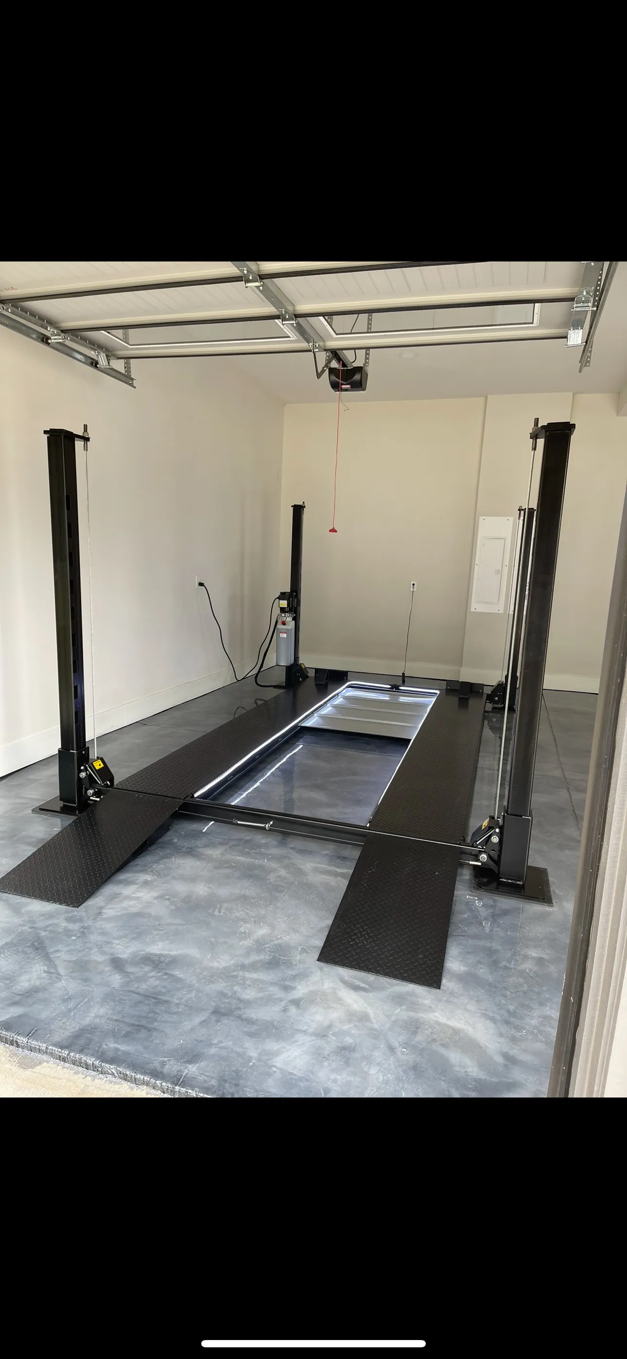 Four-post lift with ramps down, ready to drive on.